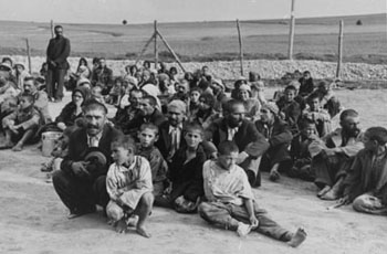 Eine Gruppe von Sinti und Roma nahe dem Zaun des KZ Belzec warten auf Anweisungen ihrer deutschen Bewacher. Belzec, 1940. Quelle: USHMM, courtesy of Archiwum Dokumentacji Mechanicznej.