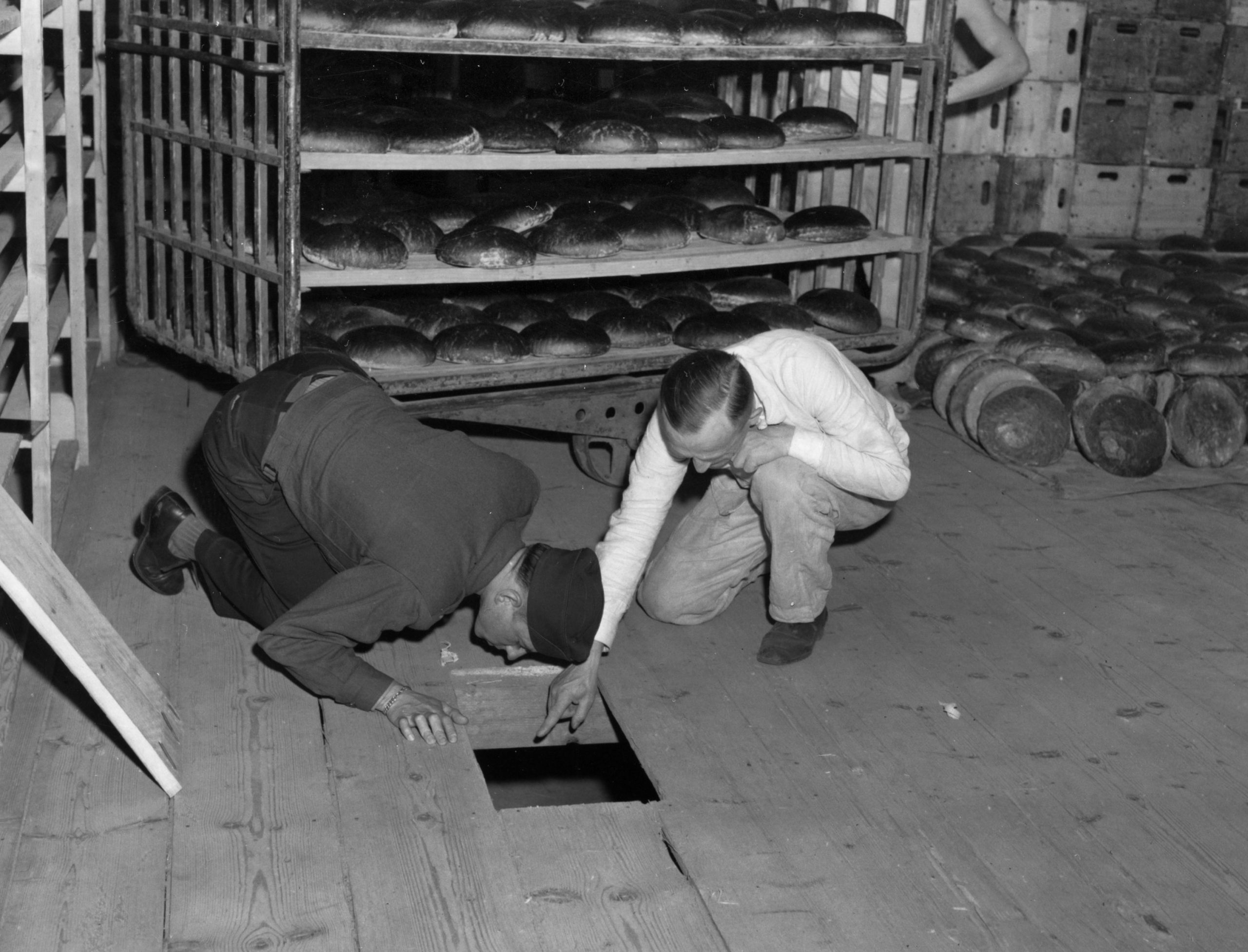 Ein US-Offizier und ein deutscher Kriminalbeamter untersuchen eine Öffnung im Boden der Nürnberger Bäckerei, 1946.