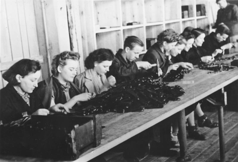 Polnische Zwangsarbeiter und Zwangsarbeiterinnen an Maschinen in einer Gewehrfabrik